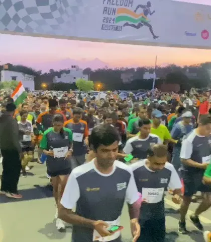 The starting line buzzes with energy as a crowd of runners begins the Freedom Run at dusk.