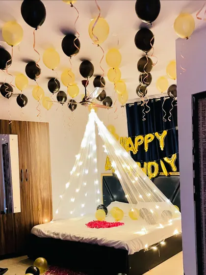 The black and gold birthday room decor, showing the 'Happy Birthday' balloons and the fairy light canopy creating a cozy and celebratory atmosphere.