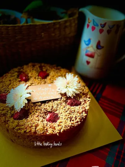 A strawberry and blueberry crumble cake, decorated with white flowers for a simple, elegant look. The crumble topping adds a wonderful texture.