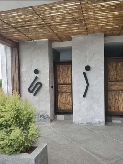 Creative and rustic washroom design for a commercial space. This project uses concrete walls, bamboo-detailed doors, and unique signage to create a memorable and thematic user experience.