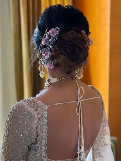A textured bridal bun adorned with soft lilac-colored flowers, perfect for a daytime wedding or to match a pastel lehenga.