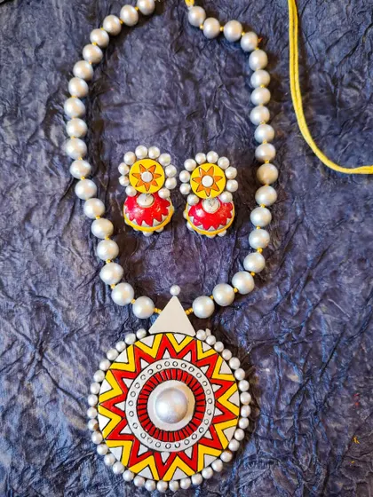 A unique terracotta jewelry set with pearl-like beads and a sun-inspired mandala pendant. This piece is perfect for special occasions like Holi or Women's Day celebrations.