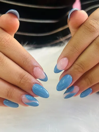 A chic and modern blue manicure. This set features a mix of solid blue nails and accent nails with a sheer base and abstract pink swirls.