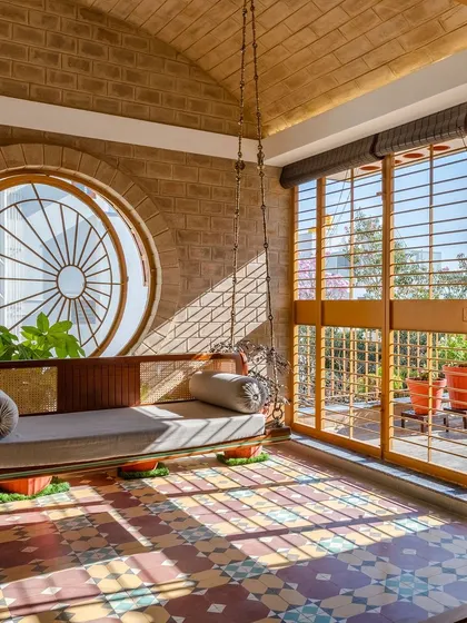 A quiet corner in the Audumbara house, where light, texture, and tradition meet. The vaulted brick ceiling, patterned cement tiles, and a large circular window create a serene, sunlit space that connects the indoors with the terrace garden.