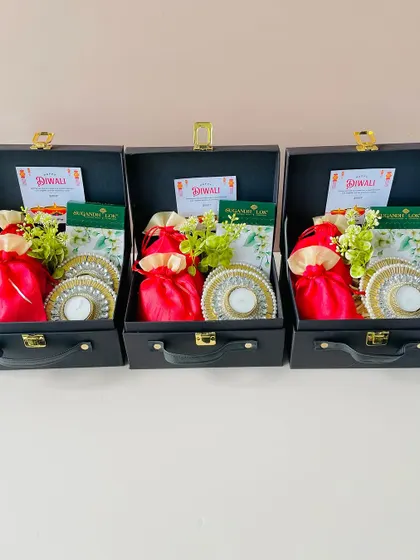 Here is a set of three identical suitcase hampers, prepared for a bulk corporate order. Each contains festive diyas and goodies, ensuring consistency and quality across all gifts.