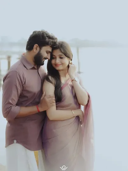 A romantic pre-wedding photo by the water, capturing a quiet and intimate moment between the couple in coordinated outfits.
