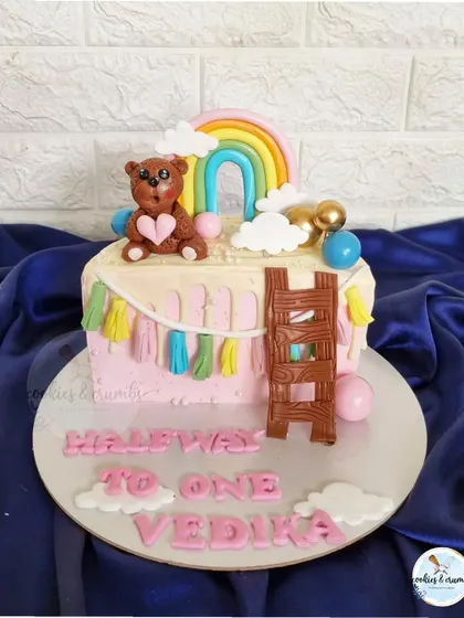 Another take on the "Halfway to One" theme, this half-cake features a cute teddy bear, a rainbow, and a colorful tassel garland made of fondant.