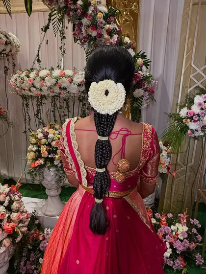 A full-length view of the segmented braid, showing how it complements the bride's half-saree. This is a wonderful hairstyle choice for coming-of-age ceremonies or other traditional events.