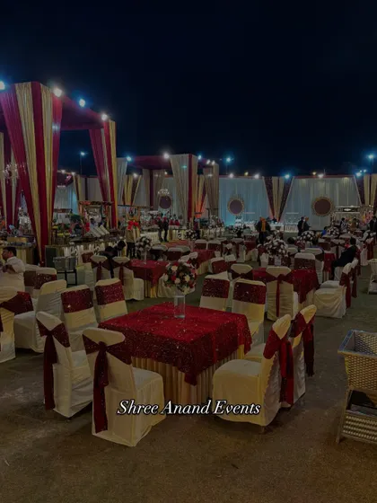 An overview of the guest dining area at an outdoor wedding. The tables are elegantly set with red and white linens and chair covers, creating a classic and formal atmosphere for the reception.