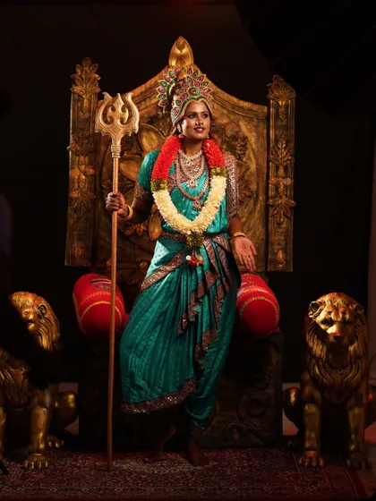 Channel your inner goddess with this stunning Devi costume, complete with a teal saree, elaborate jewelry, and a powerful trident prop.