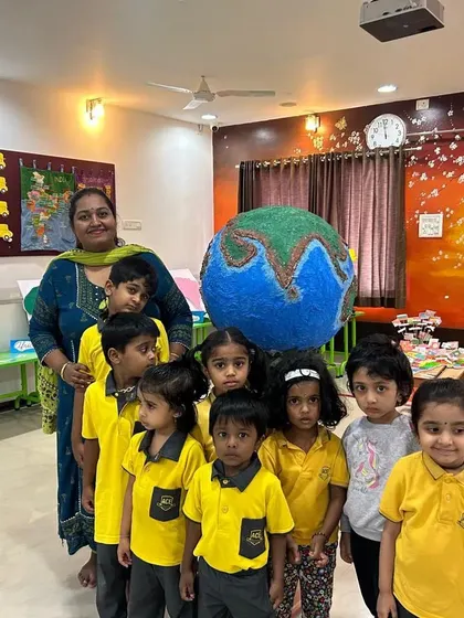 The children proudly stand with a teacher and their giant paper-mache Earth. Projects like these make learning about our planet a memorable and collaborative experience.