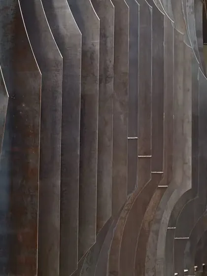 A detail of the undulating metal screen at the Automobile Design Studio, showcasing the interplay of light and shadow on the raw steel. This feature is a testament to our philosophy of finding poetry in industrial materials and forms.