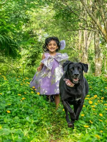 Pure, unadulterated joy. A little girl and her black Lab, Bagheera, run towards the camera through a field of green and yellow, their happiness absolutely infectious. This is the kind of energetic, candid moment I love to capture.