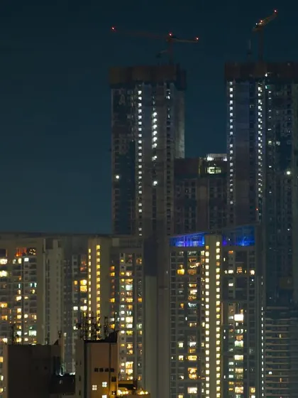 The crescent moon hangs in the night sky next to a pair of towering, under-construction skyscrapers in Mumbai.