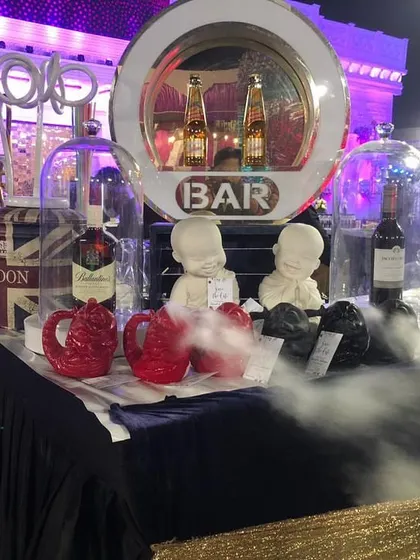 An artistic bar display with drinks and props under glass cloches, creating a curious and visually interesting setup for guests.