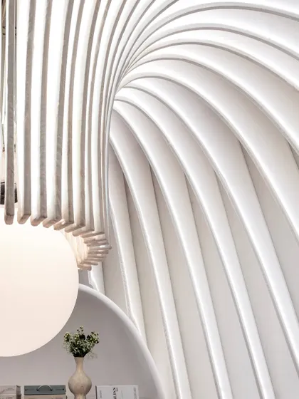 A close-up view looking up at the illuminated curves of the fabric fins and the custom chandelier. This detail showcases the precision and artistry involved in turning a soft material like fabric into a structural and sculptural element.