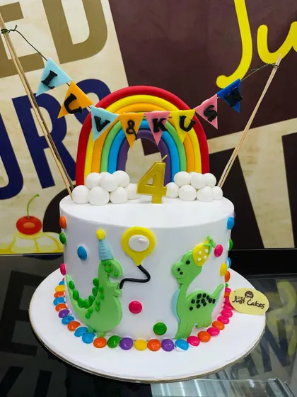 A cheerful 2kg cake with party dinosaurs, a rainbow, and a colorful bunting topper.