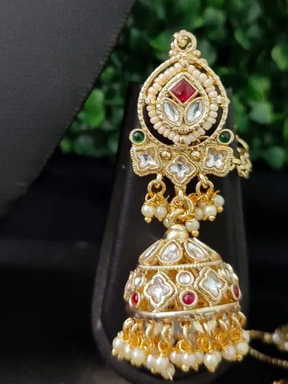 A classic kundan jhumka with red and green stones and pearl drops. This versatile rental earring can be paired with many different necklaces.