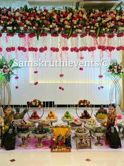 A beautiful baby shower setup with a floral arch of pink and white roses. The hanging carnation strings and an elaborate display of offerings create a delicate and sophisticated look for the mother-to-be.