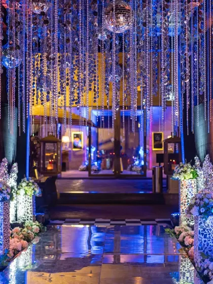 The entrance to a 'Disco Deewane' themed sangeet. A tunnel of hanging crystals and disco balls, with a reflective floor, immediately sets a glamorous and high-energy party vibe.