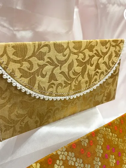 A close-up of the elegant brocade envelope, showing the delicate pearl lace trim. It's a beautiful alternative to a standard paper envelope for giving cash gifts.