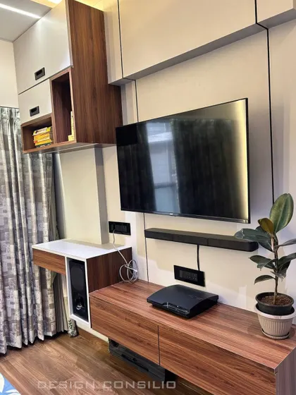 A compact yet functional TV unit setup in a bedroom. The design includes a floating console, a wall-mounted shelf for a soundbar, and overhead cabinets, making it a perfect multi-purpose entertainment and storage solution.