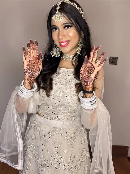 A fun pose showing off her beautiful henna. The makeup is bold enough to balance the traditional elements of her look.
