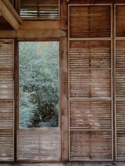 The play of light through the woven wooden panels inside the Moira studio. These surfaces are designed to filter sunlight and allow for ventilation, creating a comfortable and dynamic interior atmosphere.