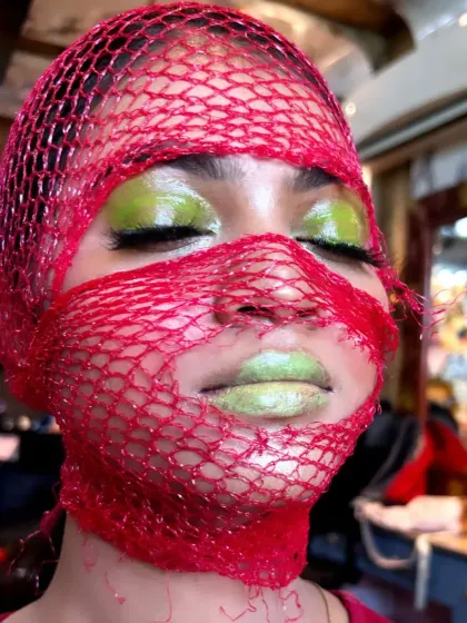 A creative makeup look from a class demo, using a net and bold colours to create an avant-garde effect.