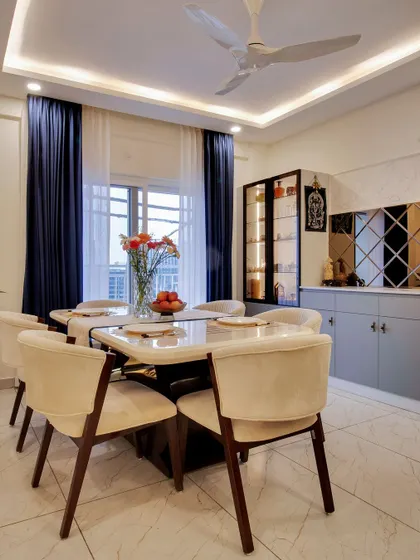 The full dining setup, with a six-seater table, plush chairs, and elegant blue curtains that add a touch of drama and colour.