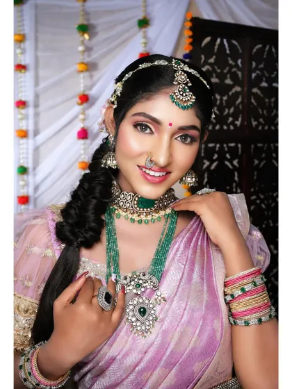 This model looks absolutely stunning in a lavender saree and a heavy emerald and polki jewellery set. The matha patti and layered necklaces create a truly regal look.