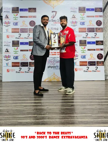 A winner proudly holding his trophy at the "Back to the Beats" event.