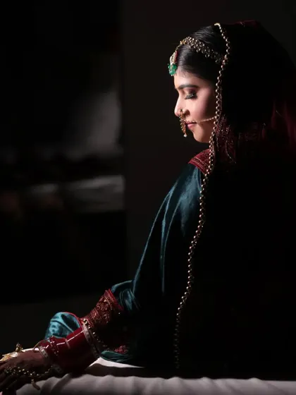 Let us capture the essence of elegance and style. A side profile of the bride in a dark, dramatic setting, looking like a classic painting.