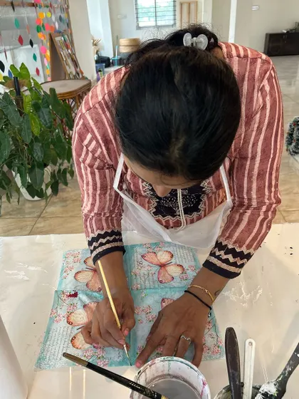 A participant carefully applying a design to a bottle during a decoupage workshop.