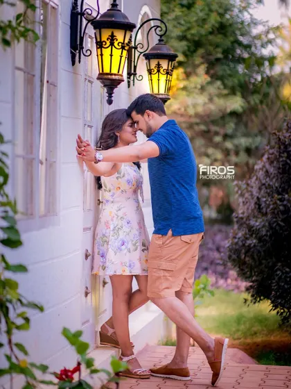 A romantic and intimate moment by a wall with vintage lanterns. The couple's casual outfits and their close embrace create a very sweet and timeless feel.