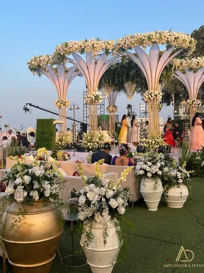 A wide view of the elegant white wedding setup, with large floral urns and a grand mandap structure that perfectly complements the outdoor lawn venue.