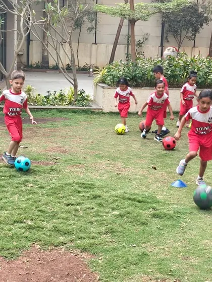 Kids running and dribbling on a grassy field, enjoying the freedom and fun of our outdoor football sessions.
