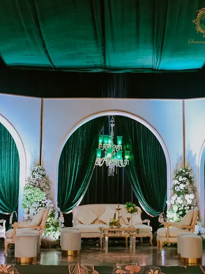 A full view of the elegant lounge area on the stage, providing a luxurious and comfortable space for the family against a backdrop of emerald drapes and chandeliers.