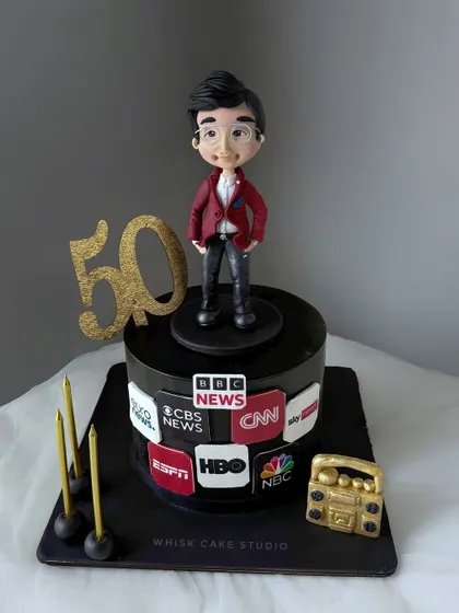 A 50th birthday cake for a media professional. The cake is decorated with logos of famous news channels and features a handcrafted caricature of the birthday boy.