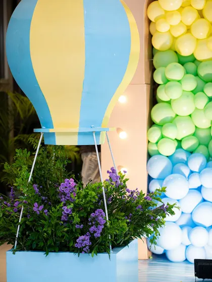 A hot air balloon prop filled with flowers, set against a wall of colorful balloons. This creative detail adds a touch of elegance to the playful travel theme.