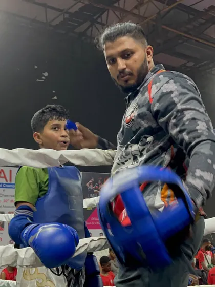 Focus before the fight. I am preparing one of my young students for his bout at the national level, ensuring his gear is secure and his mind is clear.
