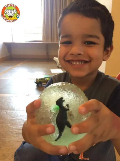 This happy explorer proudly displays a dinosaur he excavated from a gelatin "ice block." It's a fun sensory activity that teaches kids about fossils and excavation.