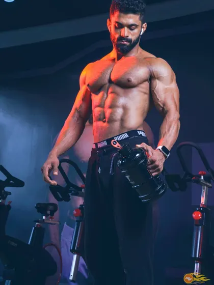 Staying hydrated is crucial for performance and muscle fullness. This shot captures a moment of recovery between sets, with a focus on core and arm definition.