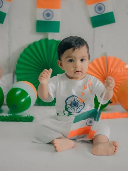 A full-body shot showing the baby sitting confidently in the middle of the patriotic setup. His alert expression is captivating.