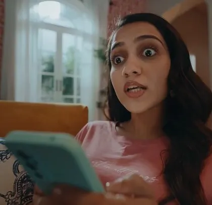 A still from a commercial for the game Bullet Echo by Krafton. The character's surprised expression is the focus, and her casual, at-home outfit makes the scene feel relatable.