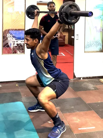 An athlete executes a perfect overhead squat, a challenging movement that tests mobility, stability, and total-body strength. I am observing closely to provide immediate feedback on form.