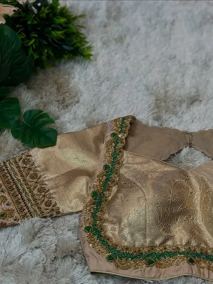 A beige blouse with a contrasting green beaded border along the neckline, paired with subtle embroidery on the sleeves.