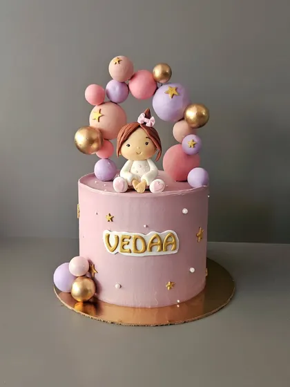 Welcoming home their lil princess. This pink chocolate truffle cake for baby Vedaa is decorated with a balloon arch and a cute, handcrafted baby figurine.