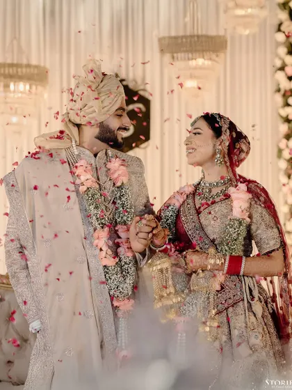 A beautiful shot of the couple under a shower of petals after their Varmala ceremony.