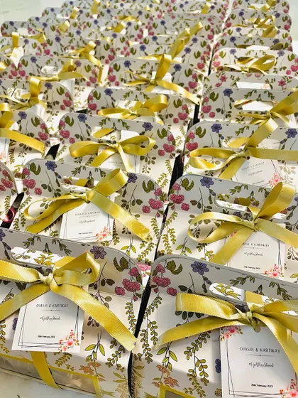 A large batch of our floral wedding favor boxes, tied with elegant yellow ribbons.